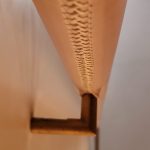 Close-up view of a hand-stitched leather handrail attached to a wall with a metal bracket.