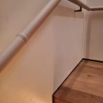 A staircase with wooden steps, a beige handrail, and a strip of lighting under the first step.