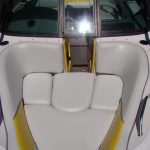 White and yellow cushioned boat seats with a glass windshield, photographed in bright sunlight.